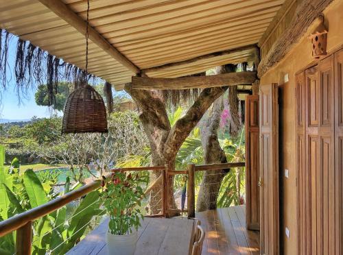 um alpendre de uma casa com uma árvore ao fundo em Casas D’Água Doce - Casa da Árvore em Ilhabela