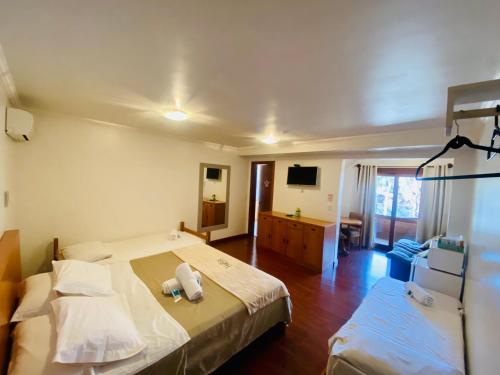 um quarto de hotel com uma cama e uma televisão em Pousada Habitue em Gramado