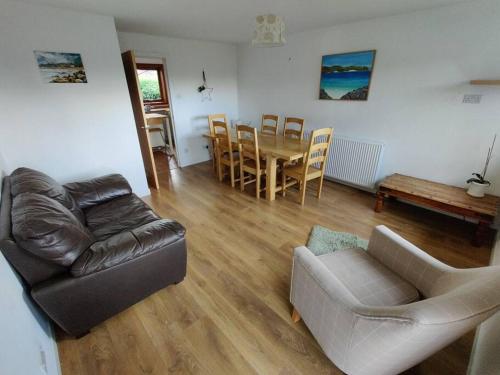 a living room with a couch and a table and chairs at 3-Bedroom Eco-house with EV charger. in Rosemarkie