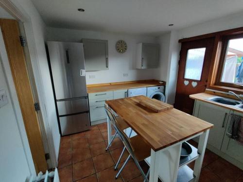 a kitchen with a wooden table and a refrigerator at 3-Bedroom Eco-house with EV charger. in Rosemarkie
