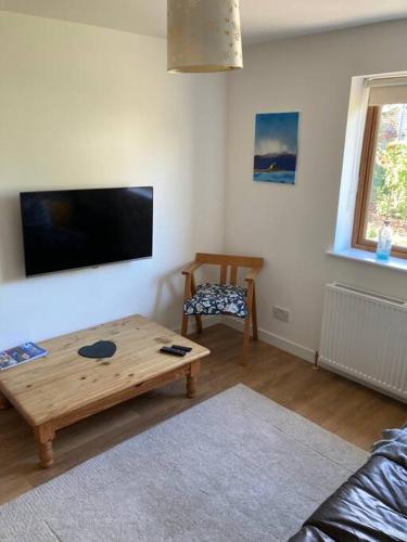 a living room with a coffee table and a flat screen tv at 3-Bedroom Eco-house with EV charger. in Rosemarkie