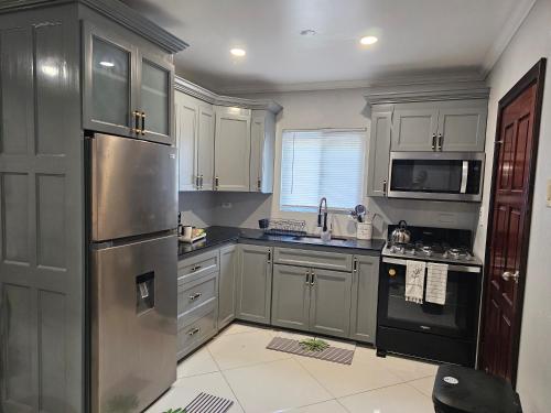 a kitchen with gray cabinets and a stainless steel refrigerator at Secret Hideaway in Ocho Rios