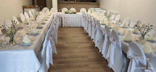 a long table with white tables and chairs with flowers at Penzión pri studničke Omastiná in Omastiná
