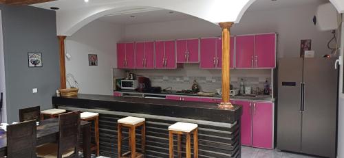 a kitchen with pink cabinets and a counter with stools at Dar redouane in El Jadida