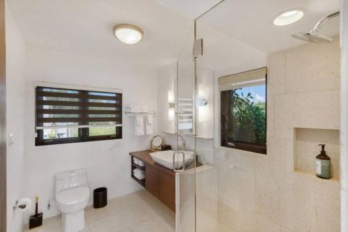 uma casa de banho com um lavatório, um WC e uma janela. em Songbird 4 BR Anguilla Villa em The Valley