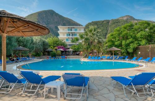 a pool at the resort with chairs and mountains in the background at Florida Blue Bay Resort & Spa in Psathopirgos