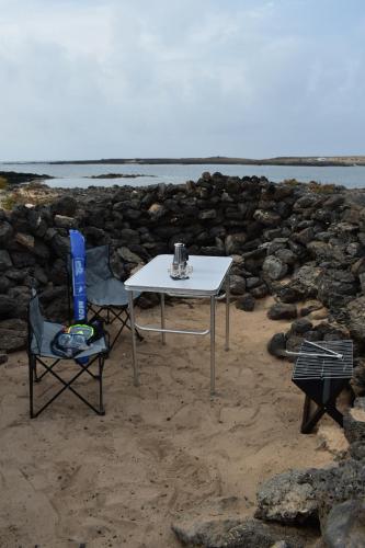 a white table and two chairs on the beach at FurgoCamper Van H1 in Tetir