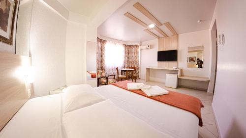 Habitación blanca con cama y mesa en Sir Hotel, en Telêmaco Borba