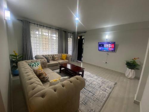 un soggiorno con divano e TV di Meru Heights a Meru