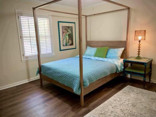 een slaapkamer met een hemelbed en een tafel met een lamp bij 3/2.5 mid island home across from Sea Palms Golf Course! in Saint Clair Estates