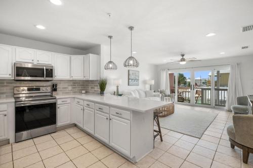 a kitchen with white cabinets and appliances and a living room at Sand Buckets Unit B, Ocean View Beach Townhouse in Mexico Beach