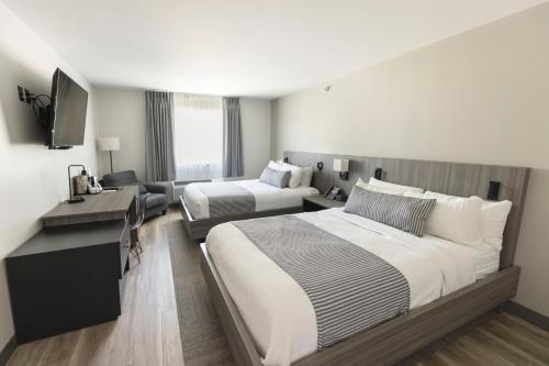 a hotel room with two beds and a desk at The Farmstead Hotel in Caruthersville