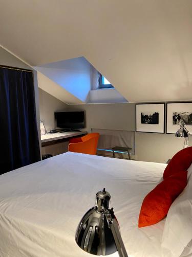 a bedroom with a large white bed and an orange chair at Hotel Casa Poli in Mantova