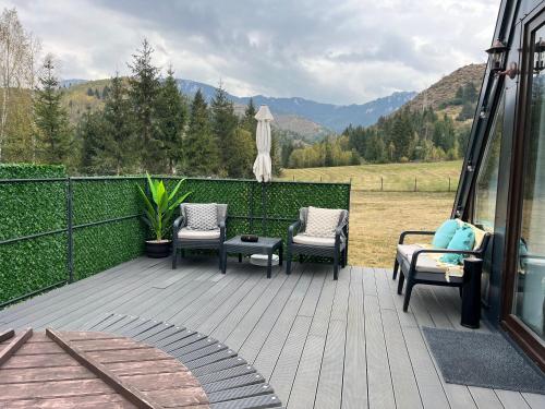 eine Terrasse mit Stühlen, einem Sonnenschirm und Bergen in der Unterkunft SouL EsCaPe in Bălan