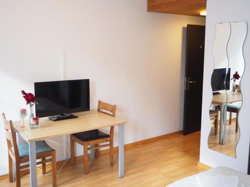 a room with a table with a television and chairs at Hotel Stadthof Glarus in Glarus