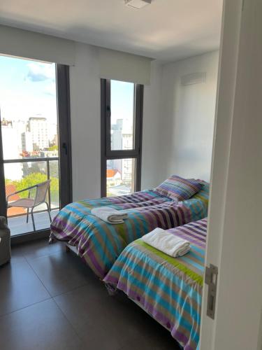 1 dormitorio con 2 camas y ventana grande en Excelente Departamento Zona Plaza Mitre con vistas a la ciudad en Mar del Plata