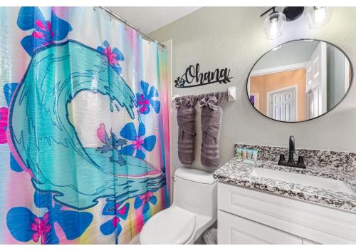 La salle de bains est pourvue d'un rideau de douche, de toilettes et d'un miroir. dans l'établissement 4BR Family Friendly Themed Pool Home Near Disney, à Davenport