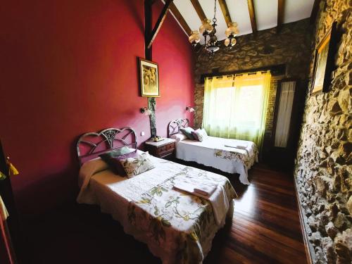 1 dormitorio con 2 camas y pared de piedra en La Casona de Picoverde en Cóbreces