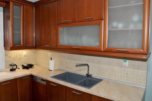 a kitchen with a sink and wooden cabinets at GRAND HOUSE METEORA in Kalabaka