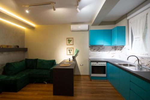 a kitchen with blue cabinets and a green couch at Melnaz Apartament 2 in Korçë