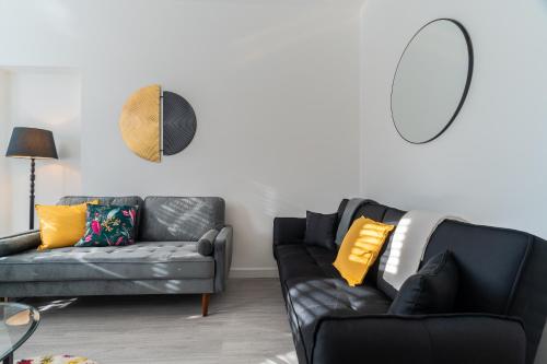 a living room with a black couch and yellow pillows at Dyke Apartment in Uddingston