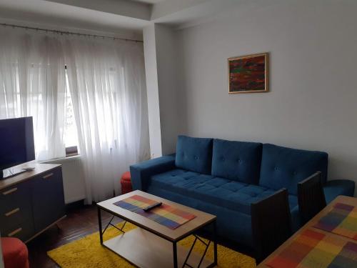 een woonkamer met een blauwe bank en een tafel bij Apartmani Zaara in Sarajevo
