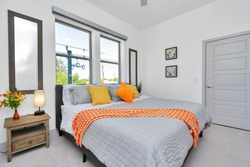 ein weißes Schlafzimmer mit einem Bett mit orangefarbenen und gelben Kissen in der Unterkunft Midtown Houston Luxury Suite at River Oaks in Houston