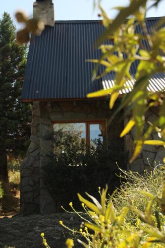 a stone cabin with a window and a metal roof at El Tranco - Casa "Bajada Poujardieu" in Junín de los Andes