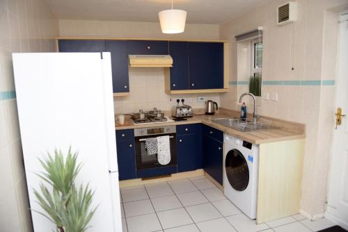a kitchen with blue cabinets and a washing machine at Gorgeous 3 bed house in Bristol in Bristol