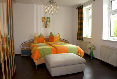 ナウムブルクにあるFerienwohnung Possögelのベッドルーム1室(オレンジと緑の枕が付いたベッド1台付)