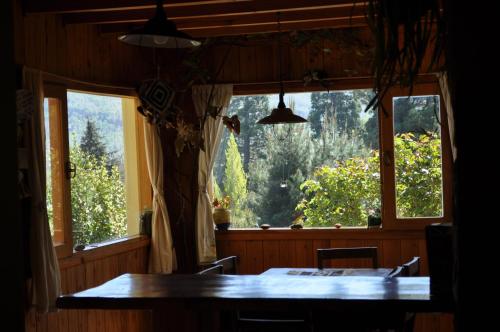聖馬丁德洛斯安第斯的住宿－Melodia natural en San Martín de los Andes，一间带桌子和大窗户的用餐室