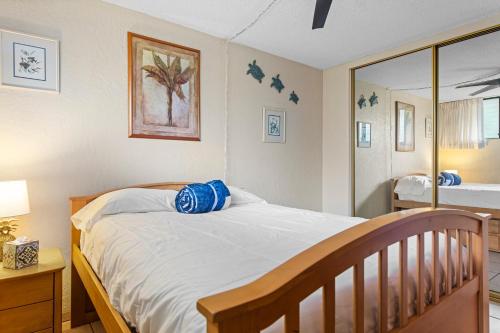 a bedroom with a bed with blue pillows on it at Maui Parkshore 209 - MCH in Kihei