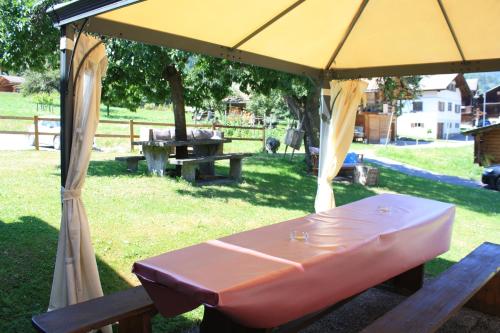 a picnic table under a yellow umbrella in a park at La Petite Auberge in Versegeres 