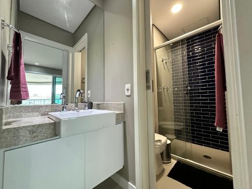 een badkamer met een wastafel, een toilet en een spiegel bij Estanconfor Praia Santos 3 - AC garagem arrumação sacada fechada in Santos