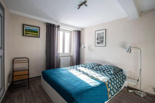 een slaapkamer met een blauw bed en een raam bij Appartement d'une chambre avec vue sur la ville et wifi a Embrun in Embrun