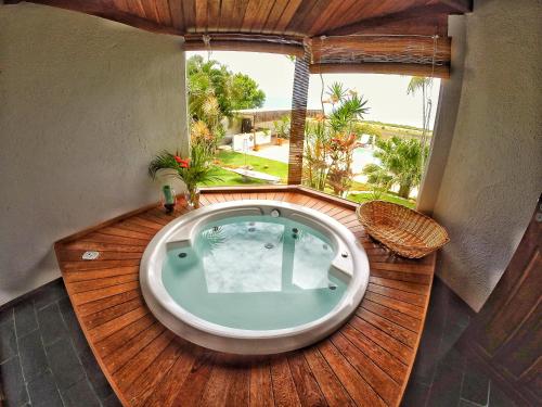 uma banheira de hidromassagem num deque de madeira com uma janela em Casa de Férias Casa Mia em Santa Cruz Cabrália