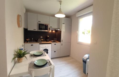 cocina con armarios blancos, mesa y sillas en Les Capitouls - avec entrée autonome, jardin & parking privé ! - en Toulouse
