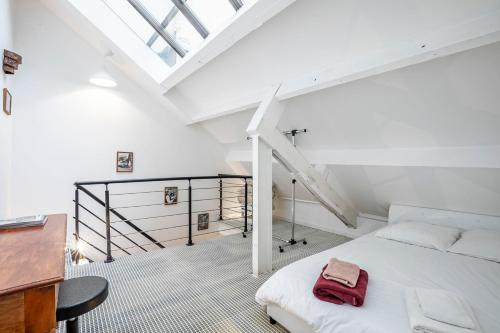 - une chambre blanche avec un lit et un escalier dans l'établissement Comme à la Maison, à Paris
