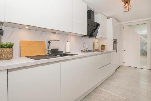 a kitchen with white cabinets and a sink at B49 - City & Messe Apartment in Cologne