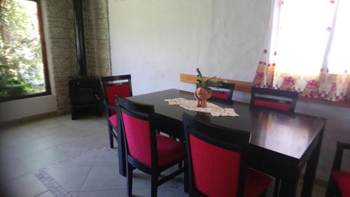a dining room with a black table and red chairs at El Tranco - Casa "Tu Lugar" in Junín de los Andes