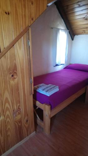 ein kleines Schlafzimmer mit einem lila Bett in einer Hütte in der Unterkunft El Tranco - Casa "Tu Lugar" in Junín de los Andes