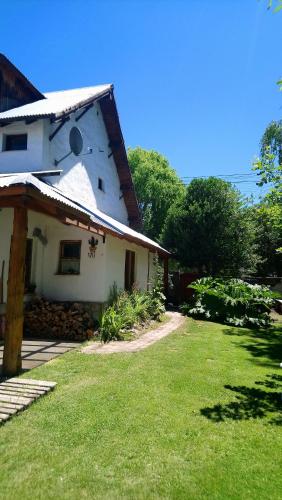a white house with a grass yard in front of it at El Tranco - Casa "Tu Lugar" in Junín de los Andes