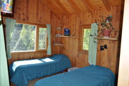 two beds in a log cabin with a window at Melodia natural en San Martín de los Andes in San Martín de los Andes