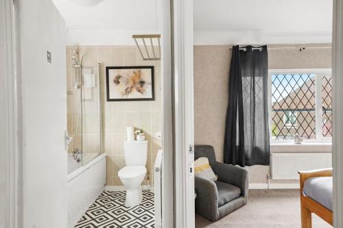 La salle de bains est pourvue de toilettes et d'une chaise. dans l'établissement BridgeCity Luxurious House in heart of Maidstone, à Maidstone
