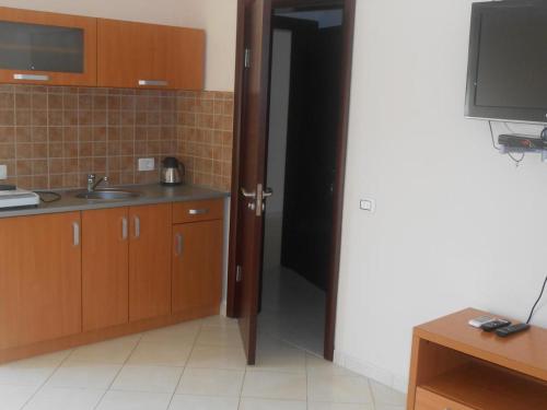 a kitchen with wooden cabinets and a sink and a television at APARTMANI LUX SEA in Utjeha