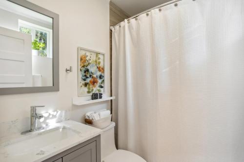 La salle de bains est pourvue d'un rideau de douche blanc et d'un lavabo. dans l'établissement Pet-Friendly Kent Vacation Rental, Walk to Lake!, à Kent