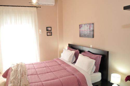 a bedroom with a bed with a pink comforter at GRAND HOUSE METEORA in Kalabaka