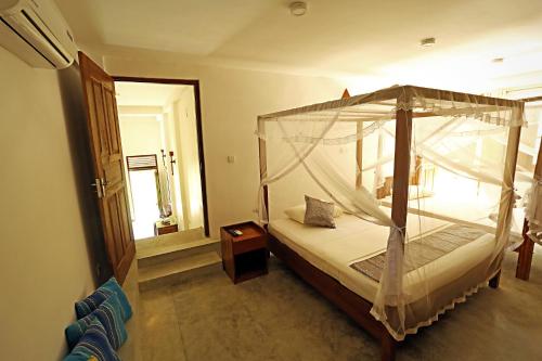 a bedroom with a canopy bed and a mirror at Beach Grove Villas in Unawatuna