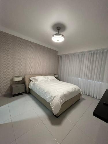 1 dormitorio con 1 cama blanca y 1 lámpara en Moderno apartamento en Naco, en Santo Domingo