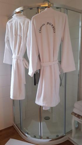 two white robes on a glass display case at Au Cœur de la Verrière du Château Burrus in Sainte-Croix-aux-Mines